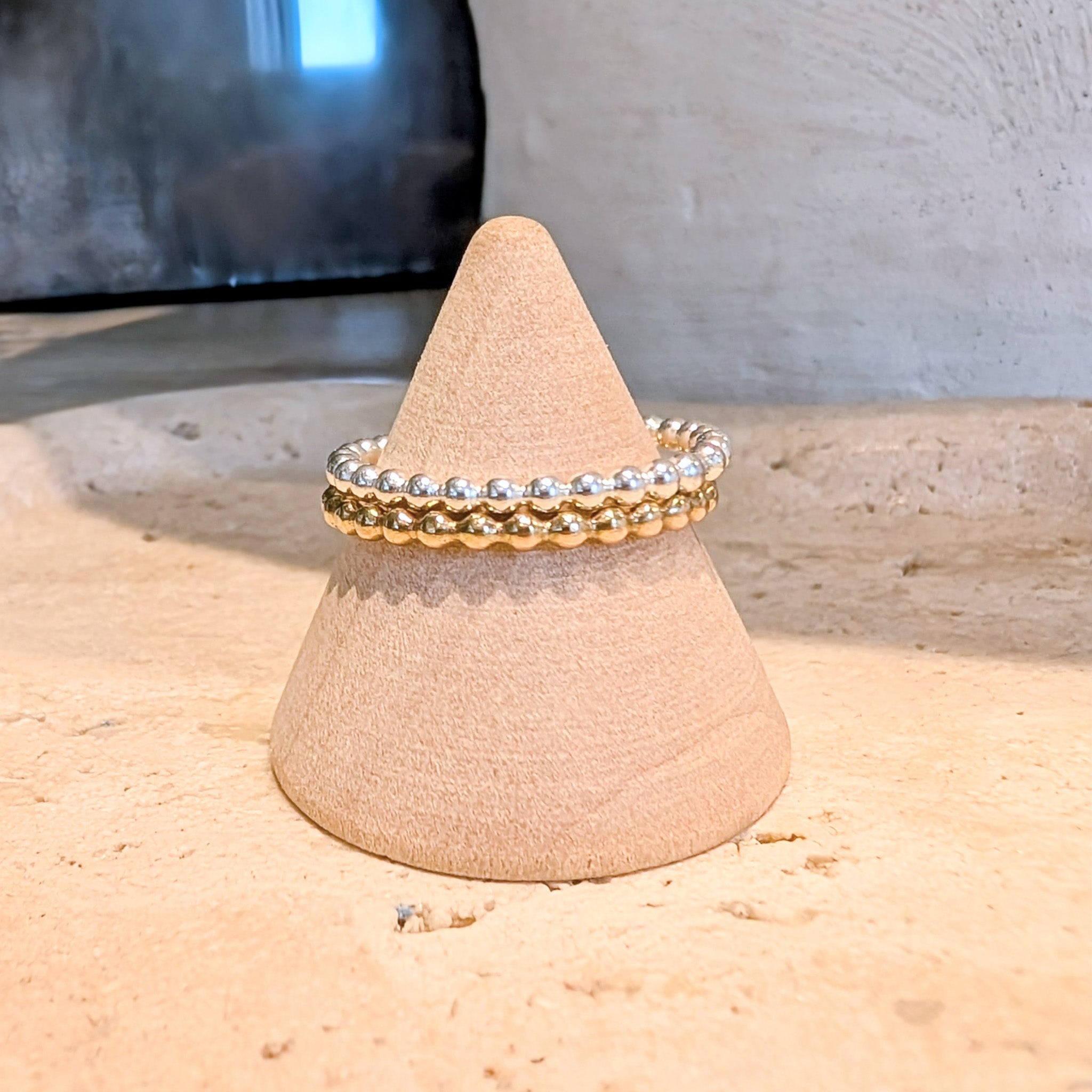 Two gold rings on a cone-shaped display stand with a neutral background